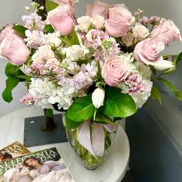 Pink roses and white hydrangeas in a clear glass vase with a ribbon