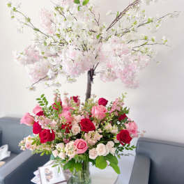 Pink and white rose arrangement in a glass vase with a flowering branch display