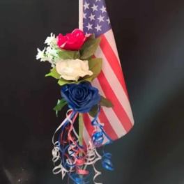Small floral arrangement with red, white, and blue roses beside an American flag