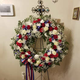 Large patriotic funeral wreath with red, white, and blue flowers on a stand