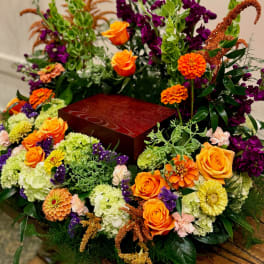 Floral arrangement around a red urn with orange roses and purple blooms