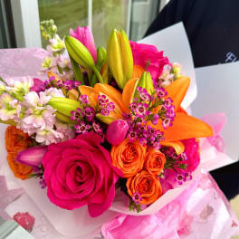 Bright bouquet of pink roses, orange lilies, and small purple flowers