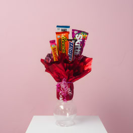 Candy bouquet in red wrapping with assorted chocolate bars in a clear vase