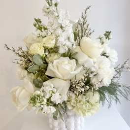 White floral arrangement in a white vase with roses and tall blooms