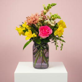 Pink rose and yellow mixed flowers in a glass vase