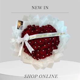 Heart-shaped bouquet of red roses with a white ribbon and sheer wrapping