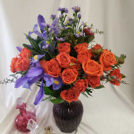 Orange roses and purple irises in a dark vase