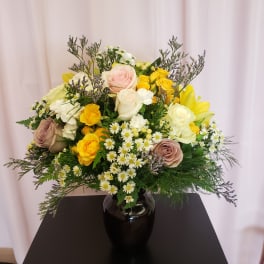 Mixed bouquet of roses and small white daisies in a black vase