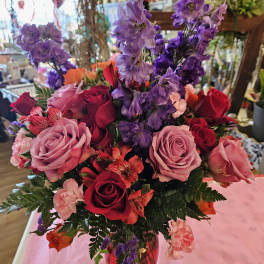 Mixed bouquet of roses and purple flowers in a glass vase