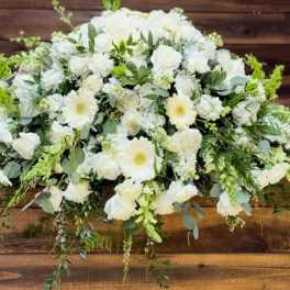 White floral casket spray with roses and daisies