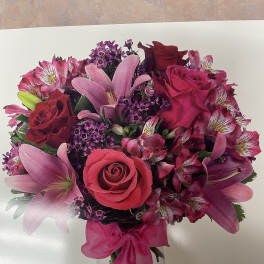 Pink and red bouquet of roses and lilies in a clear glass vase
