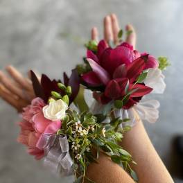Two floral wrist corsages with pink and burgundy blooms and ribbon ties