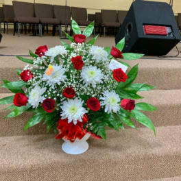 Red roses and white daisies in a white pedestal vase