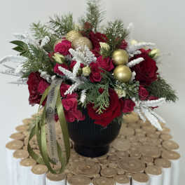Red roses and pink spray roses in a black vase with gold ornaments
