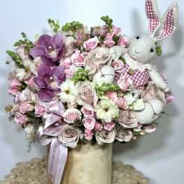 Pink and white floral arrangement with plush bunny figures in a vase