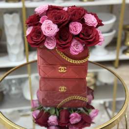 Red and pink roses arranged in a red handbag-shaped box