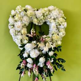 Heart-shaped white floral wreath on an easel with pink accents