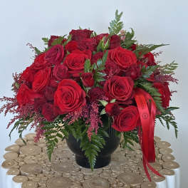 Red rose bouquet in a black vase with a red ribbon