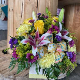 Mixed bouquet with lilies, roses, and purple daisies in a decorative box