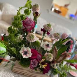 Mixed bouquet with pink roses and white anemones in a wooden base