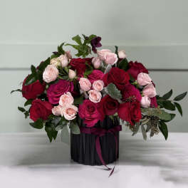 Bouquet of red and pink roses in a black vase with ribbon