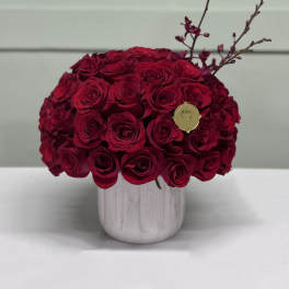 Red rose arrangement in a white vase with decorative branches
