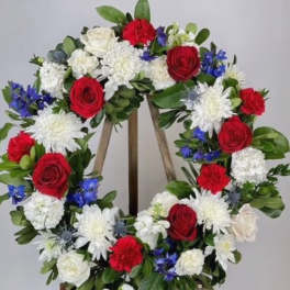 Circular floral wreath with red, white, and blue flowers on a wooden easel