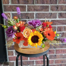 Colorful mixed flower arrangement in a white polka-dot rectangular container