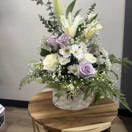 Basket arrangement with white lilies, lavender roses, and white daisies