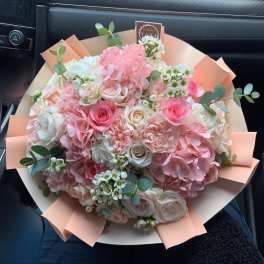 Bouquet of pink and white roses with hydrangeas and eucalyptus in peach wrap