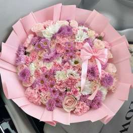 Pink and lavender bouquet with roses, daisies, and carnations wrapped in pink paper