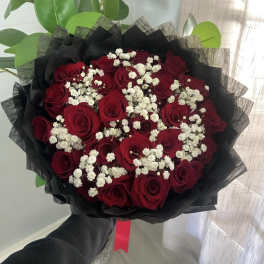 Bouquet of red roses with white baby's breath wrapped in black paper