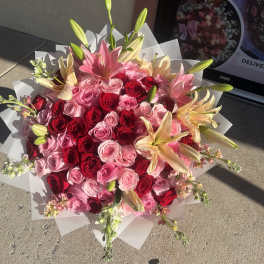 Bouquet of pink and red roses with lilies wrapped in white paper