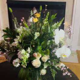 Large floral arrangement with white orchids, roses, and mixed greenery