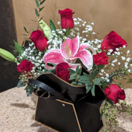 Bouquet of red roses and a pink lily in a black box
