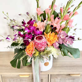 Mixed bouquet with pink, purple, and orange flowers in a white hatbox