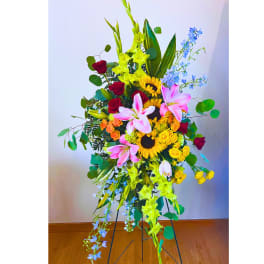 Tall floral standing arrangement with sunflowers, roses, lilies, and blue flowers