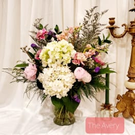 Mixed pink, white, and purple floral arrangement in a glass vase