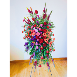 Tall standing arrangement of red, pink, and purple flowers