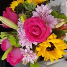 Bouquet of pink roses, yellow sunflowers, and lavender daisies