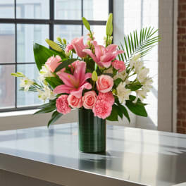 Pink lilies, roses, and carnations in a green vase