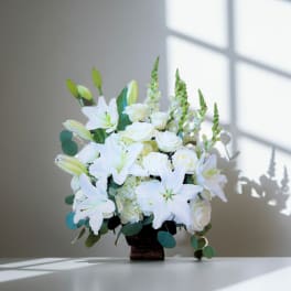 White lilies and roses arranged in a dark vase