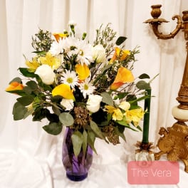 Bouquet of white daisies and yellow calla lilies in a purple vase