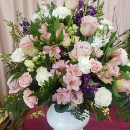 Large pastel bouquet of pink and white roses with purple flowers in a white vase