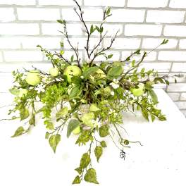 Green floral arrangement with apples in a low container