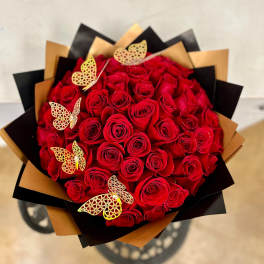 Bouquet of red roses wrapped in black and gold paper with butterfly accents
