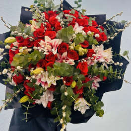 Bouquet of red roses, pink lilies, and eucalyptus with black wrap