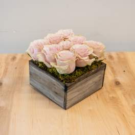 Pale pink roses arranged in a square wooden box