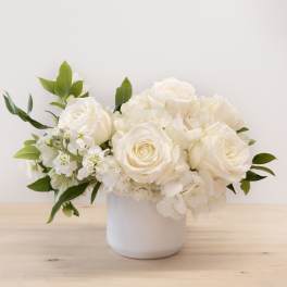 White roses and hydrangeas arranged in a white vase
