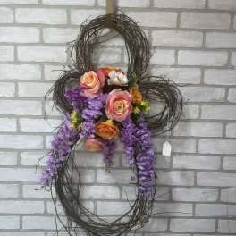 Floral wreath with purple hanging blooms and peach roses on a twig frame